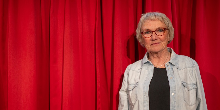 Bild på Lena Hagstedt Sergel framför ett en röd teaterridå.