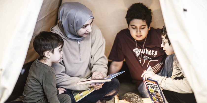 Familj har lässtund i en kåta inne i biblioteket.