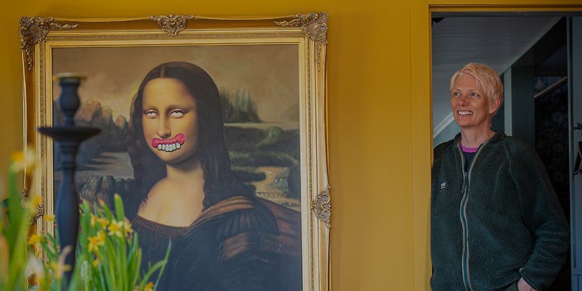 Johanna på pensionat helags står i en dörröppning, en tavla med Mona Lisa bredvid.