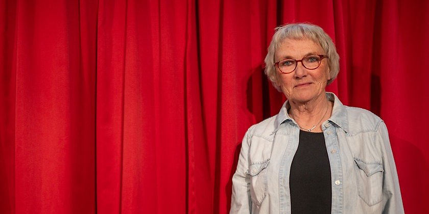 Bild på Lena Hagstedt Sergel framför ett en röd teaterridå.